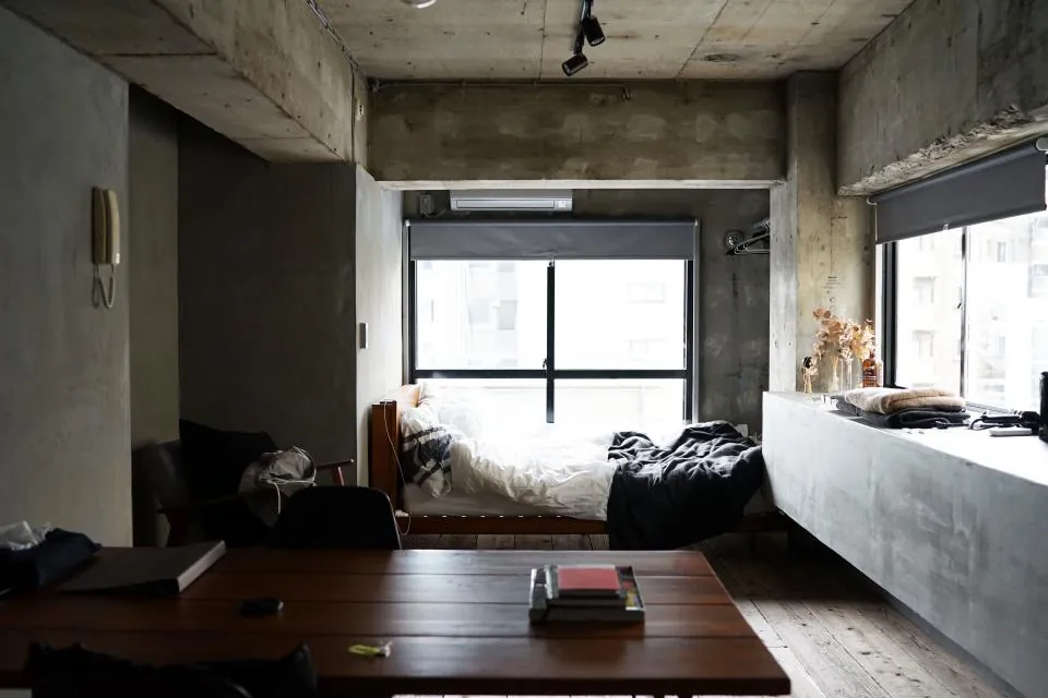 Studio apartment with a bed on a concrete plinth and a large window