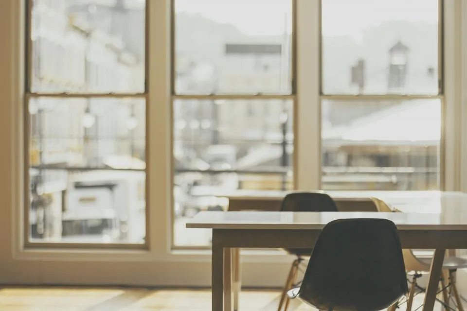 Desk and chair by a tall window in a bright study