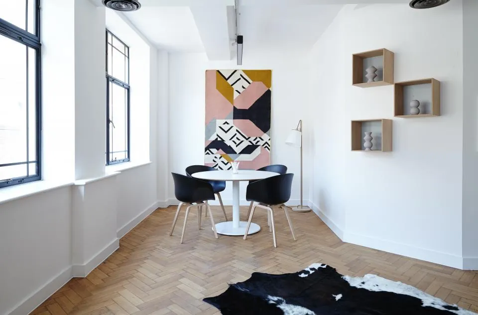 Dining nook with a round white table, wall shelves and a herringbone floor