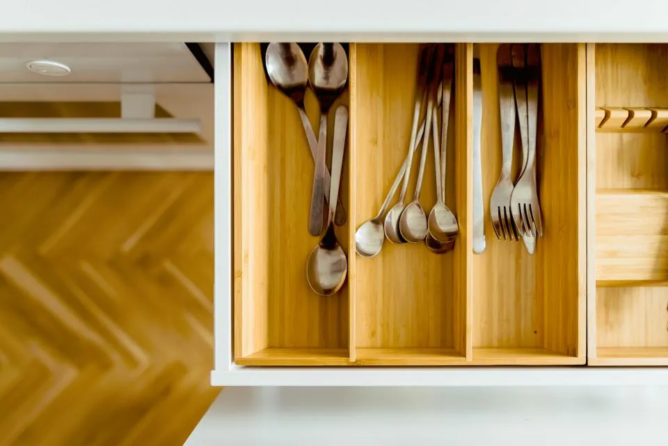 Oak cutlery drawer pulled open above a herringbone floor