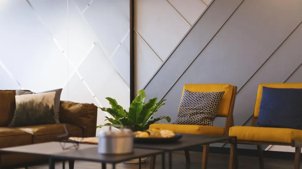 Living room with a panelled feature wall, a leather sofa and mustard armchairs